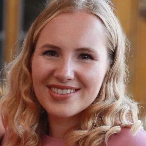 Ellie Cleasby looks into the camera while wearing a pink shirt.