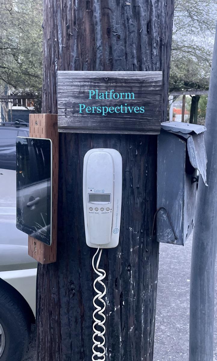 Various technologies like a landline phone and an iPad are nailed to a telephone pole. On the telephone pole, there is a sign that reads "Platform Perspectives"