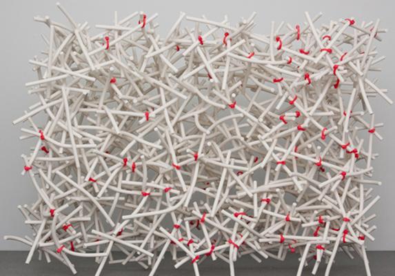 Installation art made up of white porcelain rods tied together by red plastic ties