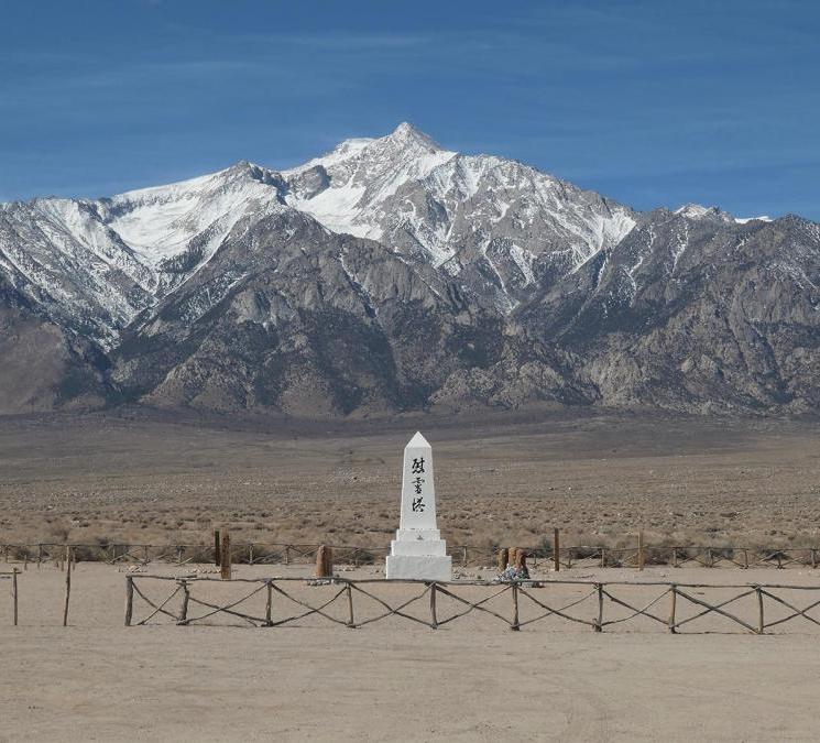 still from Manzanar Diverted: shows a japanese white stone monument in a plain in front of mountains