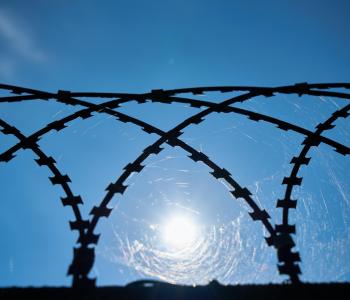 Barbed wire with the sun in the background.