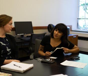 Two people sit at a table and talk to each other.