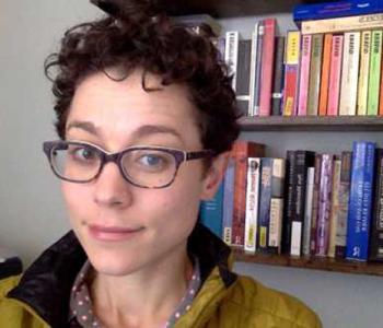 Annie Dwyer stands in front of two shelves of books.