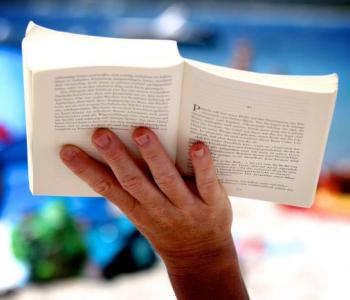 Book being held up with one hand.