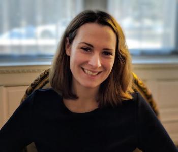 Jessica Bachman smiling at the camera in a black shirt and short hair with blurred background