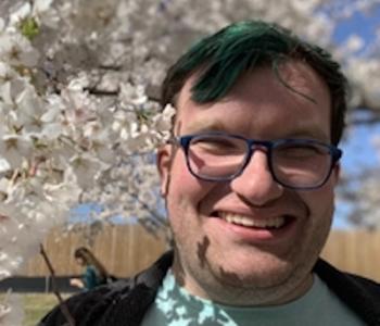 Close-up of Julian Barr smiling among cherry blossoms