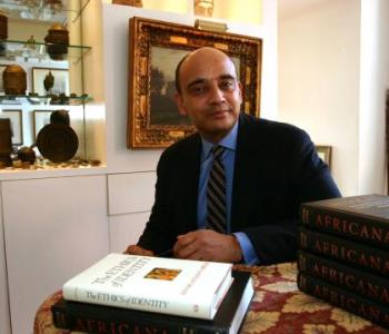 Kwame Anthony Appiah sits behind a desk with several books in front of him.