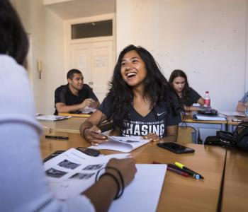 student laughing at cluster of desks with friends