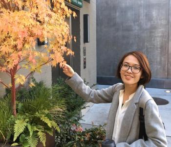 Portrait of Xin Peng standing by a golden Japanese Maple tree