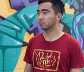 Alika Bourgette wears a red shirt while standing in front of a multicolored wall.