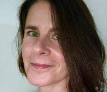 Portrait of Barbara Henry standing in front of a white wall.