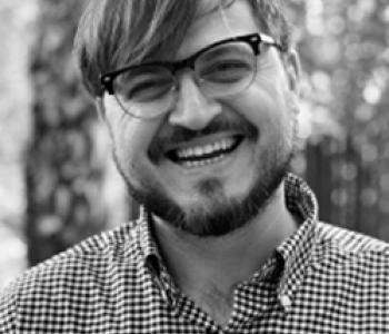 A black and white image of Darren Byler wearing glasses.