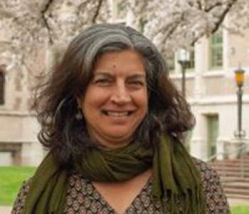 Davinder Bhowmik stands outside wearing a green scarf and patterned shirt.