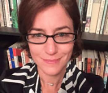 Portrait of Gillian Harkins sitting in front of a bookcase.