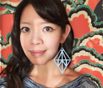 Jane Wong stands in front of a patterned wall wearing a grey shirt.