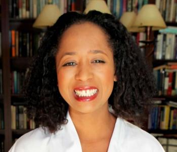 A portrait of Jasmine Mahmoud standing in front of a bookcase.