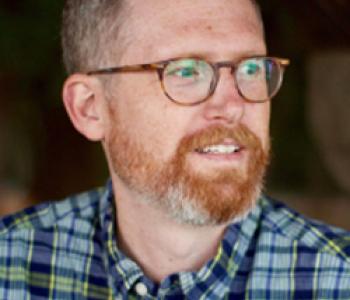 Jeffrey Knight wears a plaid shirt and glasses.