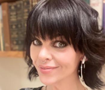 A close-up portrait of Jennifer Smith standing in front of a bookcase.