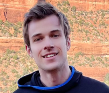 Close-up image of Joe Wilson wearing a sweatshirt while standing in front of a red rock formation.