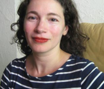 Jordanna Bailkin wears a striped shirt in front of a white wall.