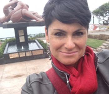 María Elena García stands outside wearing a red scarf and grey jacket.