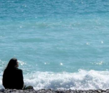 Sarah Ross sits on a beach looking toward the water.