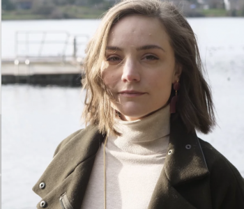 Portrait of CR Grimmer in a turtleneck and jacket with the Puget Sound behind them