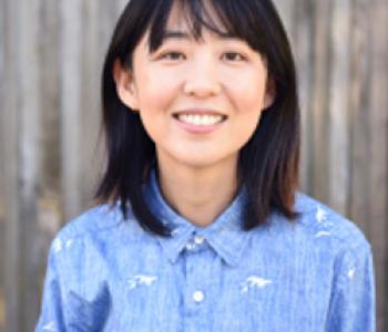 Portrait of Ellen Y. Chang standing in front of a blurred background and wearing a blue collared shirt.