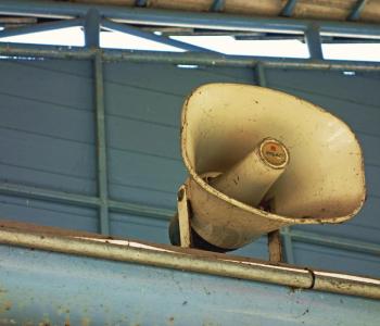 A megaphone mounted on a blue-gray wall.