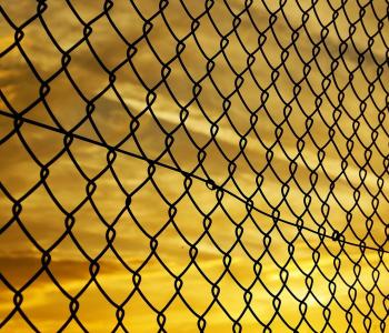 A chain link fence against the backdrop of a yellow sunset.