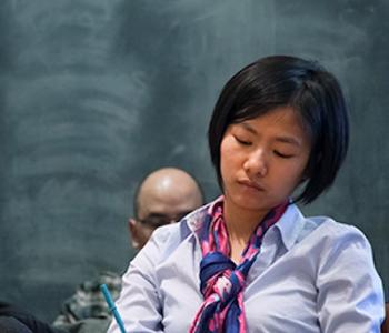 Scholar at a desk in front of a chalkboard