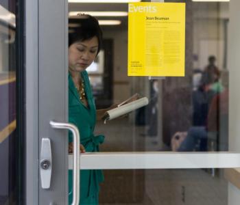 someone about to open a glass door that has a yellow event flyer on it