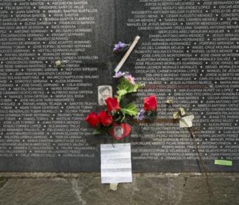 A bouquet of flowers sits at the base of a dark wall with names etched in white.