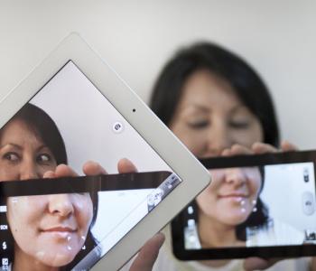 Photo is a mise en abyme with multiple digital tablets and devices fragmenting a woman.