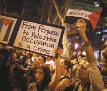 A group of protesters hold signs.