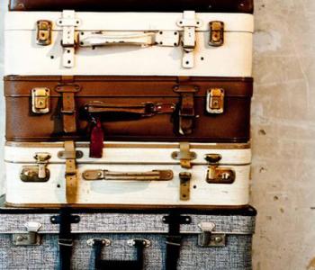 Suitcases stacked against a cream colored wall