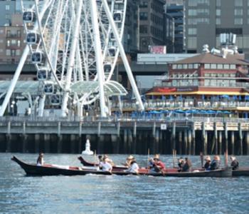 Suquamish citizens paddle two canoes past downtown Seattle.