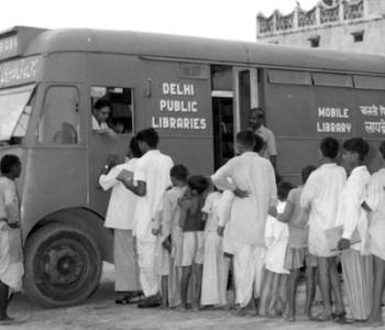 Children line up to check out books from a mobile library van in Delhi in 1957.